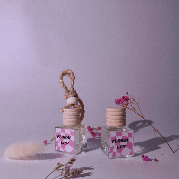 Charmeau Floral Luv - two bottles of perfume sitting next to some flowers.